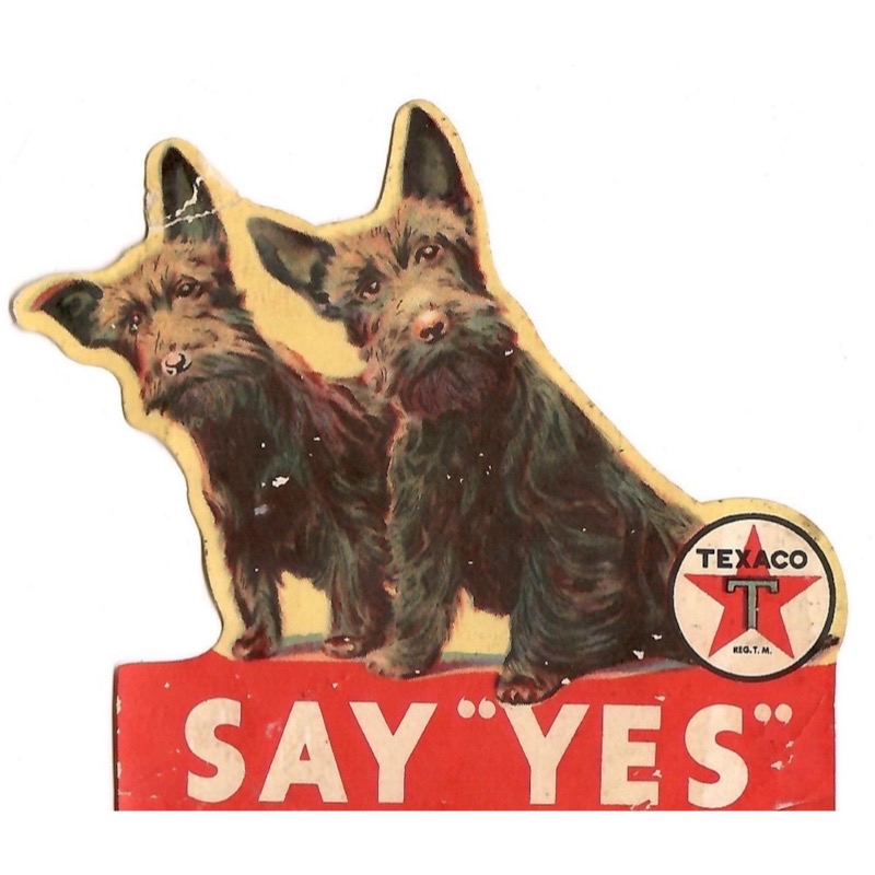 To Scottie dogs set a top a “Say Yes, Texaco,” sign.
